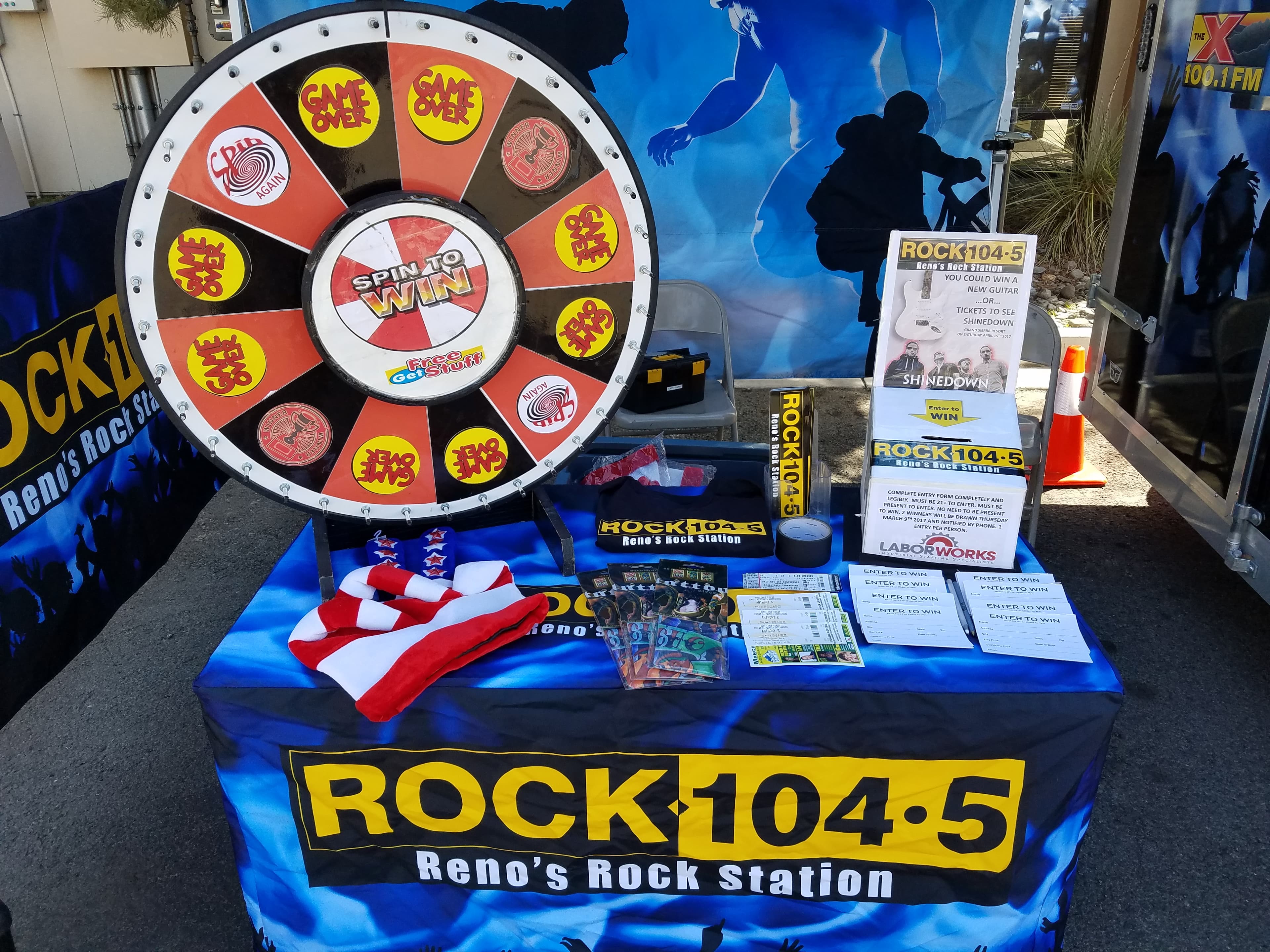 ROCK 104.5 KDOT Spin to Win prize wheel and merch table at a radio remote