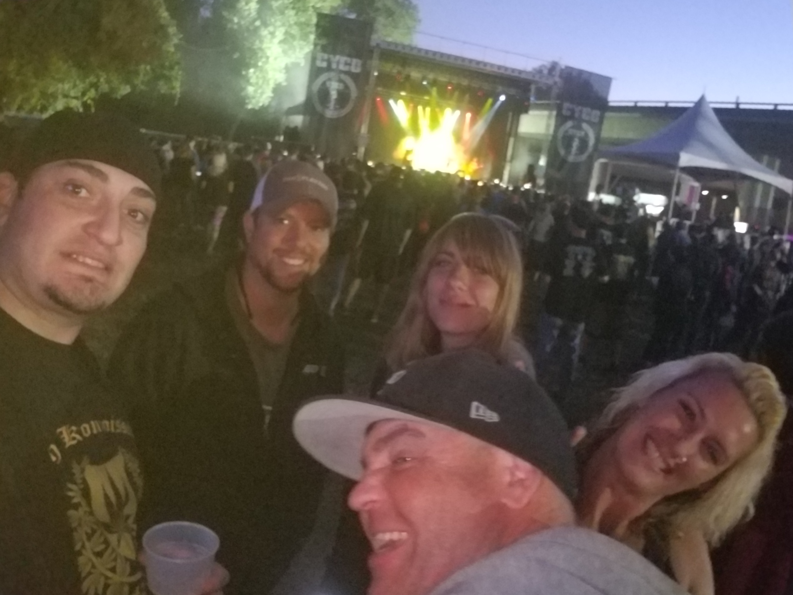Kronik with friends at night in front of a lit festival stage at Aftershock