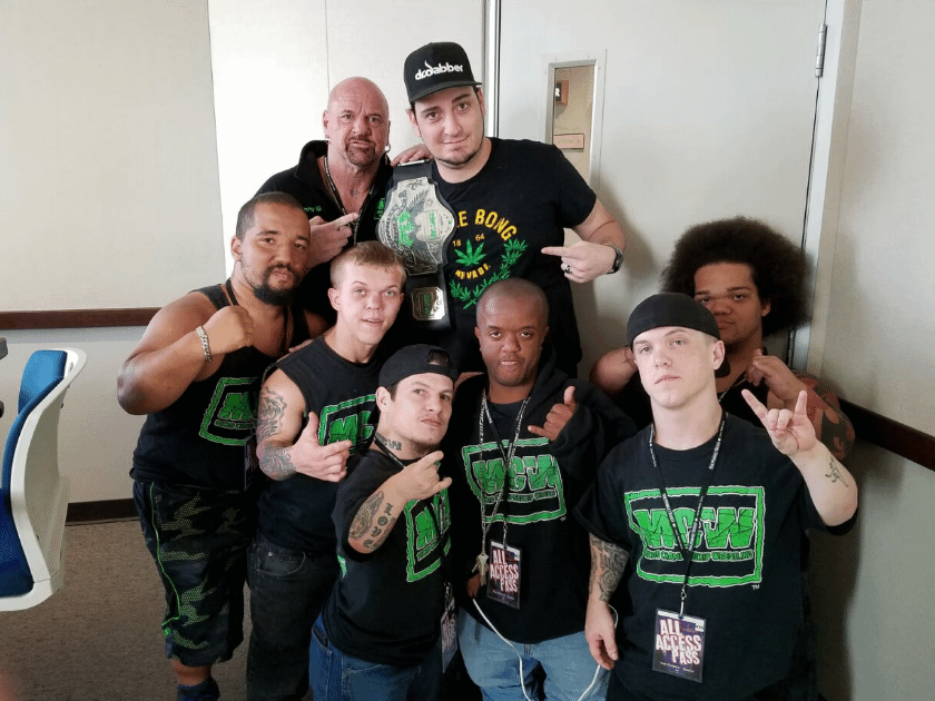 Kronik with MLW wrestlers holding a championship belt backstage with All Access passes