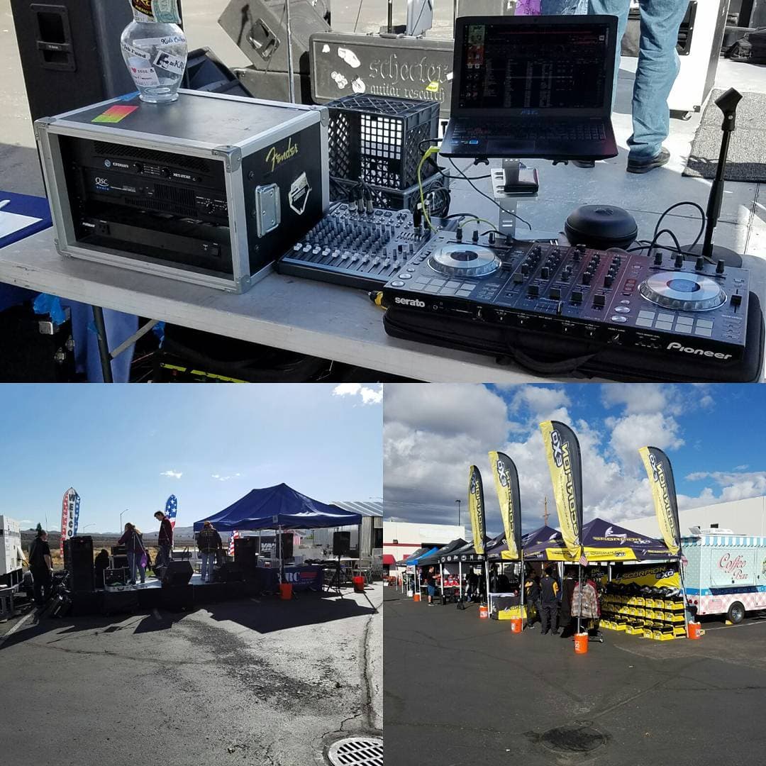Outdoor DJ setup with Pioneer Serato controller, mixer, QSC amps, and PA on a parking lot stage